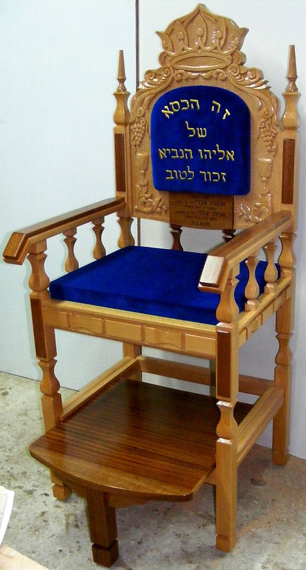 Synagogue bench with red velvet cushions used as the Throne of Elijah