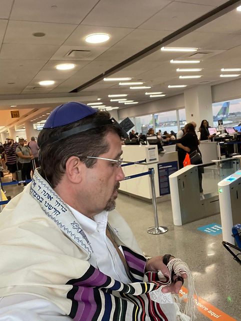 Rabbi Glantz wearing tefillin at the airport en route to a bris in Santo Domingo